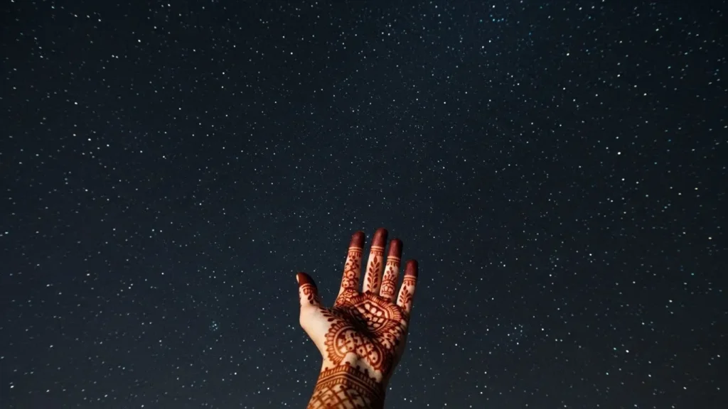 Henna-adorned hand reaching toward clear starry sky during Dubai desert safari night